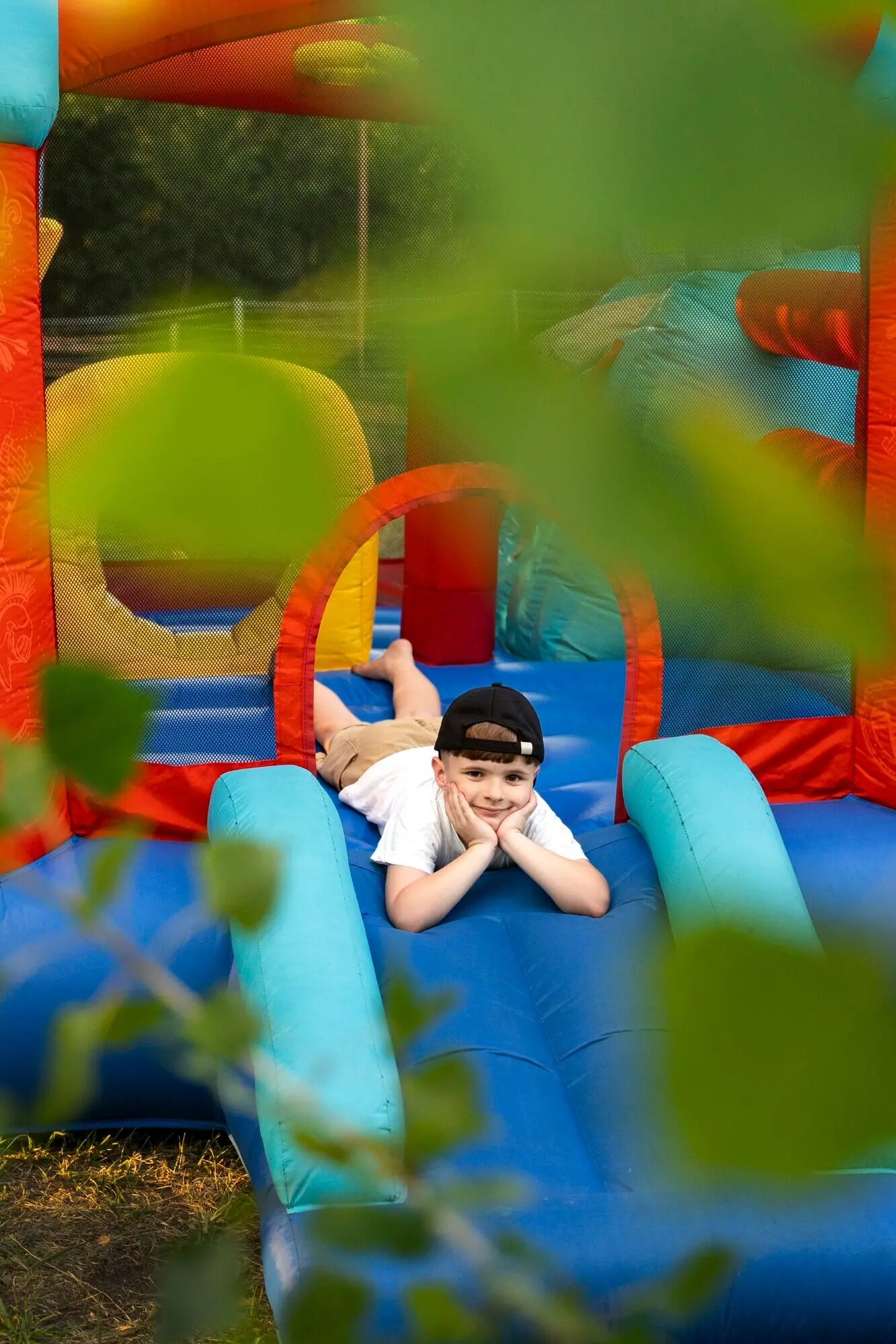Ganzkörperaufnahme eines lächelnden Jungen in einer Hüpfburg